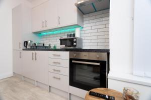 uma cozinha com armários brancos e um forno preto em The Avenue Apartments em Leeds