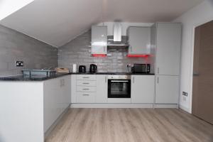 uma grande cozinha com armários e electrodomésticos brancos em The Avenue Apartments em Leeds