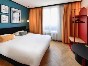 um quarto de hotel com uma grande cama branca e uma janela em ibis Styles Dijon Central em Dijon
