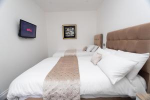 a bedroom with two beds and a flat screen tv at The Avenue Apartments in Leeds