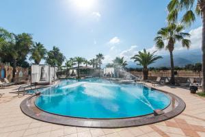 a large swimming pool with palm trees and a fountain at Oasis Studios in Malia