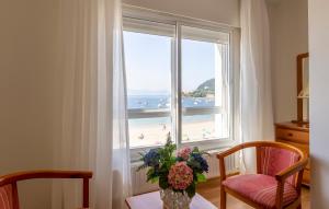 un jarrón de flores en una mesa frente a una ventana en Hotel Nautilus, en Raxó