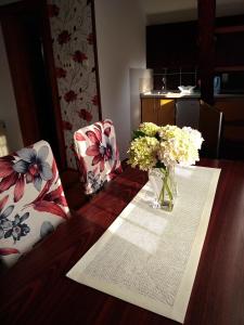 una mesa de madera con un jarrón de flores. en Sweet Apartment en Zaječar