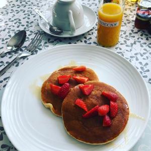 a plate of pancakes with strawberries on a table at Hotel 50 in Bournemouth