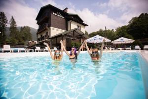 three women in a swimming pool with their hands in the air at Villa Billa in Tatariv