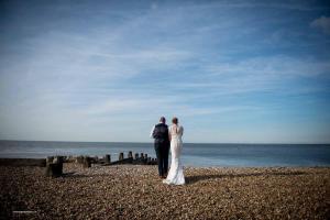 a bride and groom standing on the beach at The Marine in Whitstable