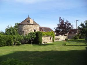 um antigo edifício de pedra com um jardim de relva em Les Grandes Vignes em Saint-Étienne-sous-Bailleul