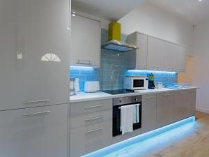 a kitchen with white cabinets and blue tiles at Live in Leeds Greenhill Bungalows in Leeds