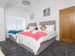 a bedroom with two beds and a wooden door at Live in Leeds Greenhill Bungalows in Leeds