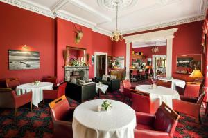 a restaurant with red walls and tables and chairs at The Greenhill Hotel in Wigton