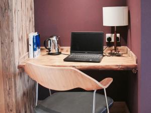 einen Laptop auf einem hölzernen Schreibtisch mit Stuhl in der Unterkunft The Lodge at Hemingford Grey House in Hemingford Grey