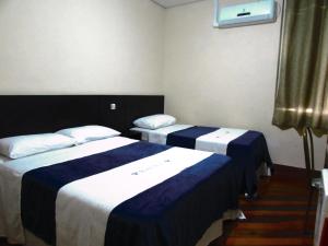 um quarto de hotel com duas camas com lençóis azuis e brancos em Hotel Minho -Próximo , 25 Março, Brás e Bom Retiro Esquina com rua dos Eletrônicos em São Paulo