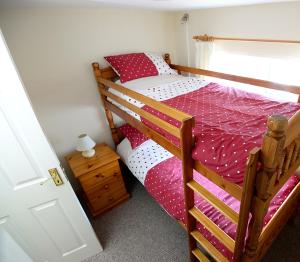 a bedroom with a bunk bed with red and white sheets at Village Cottage Bushmills in Bushmills