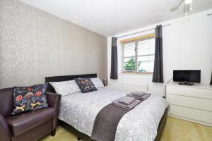 a bedroom with a bed, chair and a lamp at Harlinger Lodge Annexe in London
