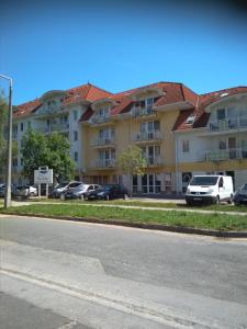 a large apartment building with cars parked in a parking lot at KarosPool Apartman in Zalakaros +5 photos
