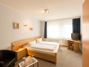 ハイリゲンハーフェンにあるJust sleep, Heiligenhafenのベッドとテレビ付きのホテルルーム