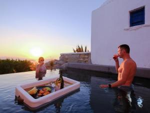 a man sitting in the water with a box of food at Ostraco Suites in Mikonos