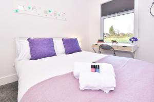 a bedroom with a white bed with purple pillows and a window at Townhouse @ Henry Street Crewe in Crewe