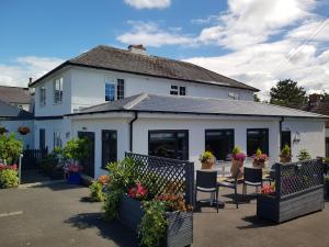 a white house with a patio with chairs and flowers at Hensleigh House in Charmouth