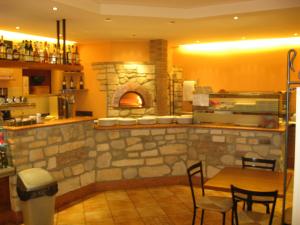 un restaurante con horno de pizza, mesa y sillas en Laghetto ai Portici, en Pastrengo