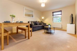 ein Wohnzimmer mit einem Sofa und einem Tisch in der Unterkunft Guest Homes - Hillbrook House Apartment in Great Malvern