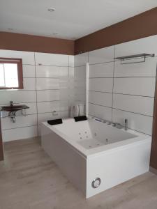a large white bath tub in a room with a window at Motel Caldas in Caldas de Reis