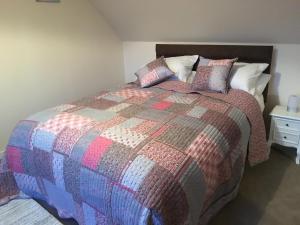 a bedroom with a bed with a colorful blanket and pillows at Hillside in Kyleakin