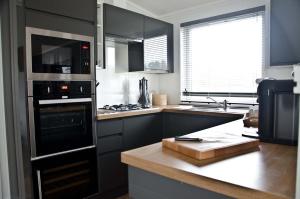 uma cozinha com armários pretos e um forno com placa de fogão em Hollicarrs - Honeycomb Lodge em York