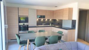 a kitchen with a table and some green chairs at Appartement Laudon in Sévrier