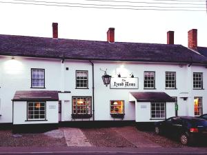 a white inn with a car parked in front of it at The Hood Arms in Kilve