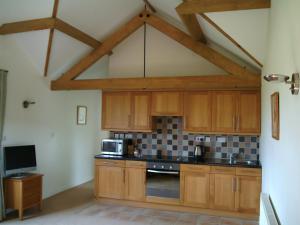 uma grande cozinha com armários de madeira e uma televisão em Hook Farm Cottages em Royal Wootton Bassett