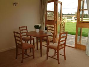 een tafel en stoelen met een fles wijn erop bij Hook Farm Cottages in Royal Wootton Bassett