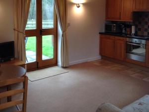 a living room with a kitchen with a table and a microwave at Hook Farm Cottages in Royal Wootton Bassett