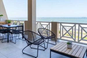 a balcony with a table and chairs and the ocean at Waterfront Getaway, 2 Bedroom Seaside Bliss in Umdloti