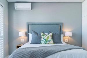 ein Schlafzimmer mit einem Bett mit blauen Wänden und zwei Lampen in der Unterkunft Waterfront Getaway, 2 Bedroom Seaside Bliss in Umdloti