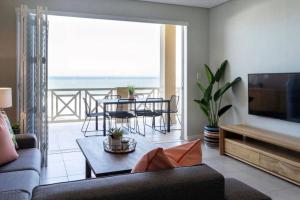 ein Wohnzimmer mit einer Couch und einem Tisch mit Stühlen in der Unterkunft Waterfront Getaway, 2 Bedroom Seaside Bliss in Umdloti