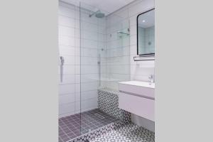 ein Badezimmer mit Dusche, Waschbecken und Spiegel in der Unterkunft Waterfront Getaway, 2 Bedroom Seaside Bliss in Umdloti + 10 Fotos