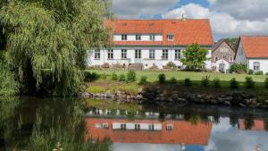 una casa blanca con techo rojo junto a un río en Sonnerupgaard Hotel & Konference, en Kirke-Hvalsø