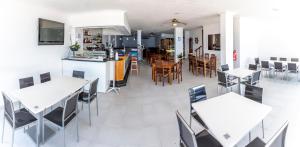 cocina y comedor con mesas y sillas blancas en Hotel Nautilus, en Raxó