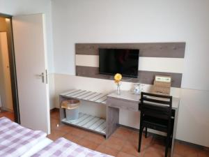 Schlafzimmer mit einem Schreibtisch und einem TV an der Wand in der Unterkunft Hotel Haus Hildegard - Garni 3 Sterne superior in Niederkrüchten