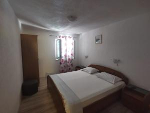 a bedroom with a white bed and a window at Apartmani Franceska in Bol