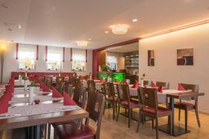 un restaurante con mesas de madera y sillas con servilletas rojas en Muellers Weingut und Weinstube im Auerberg, en Nordheim