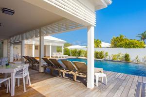 a patio with a table and chairs and a swimming pool at Hôtel La Christophine in Saint-François