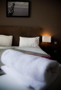 a bed with a white comforter on top of it at Hôtel Restaurant La Ribaudière in Antananarivo