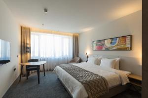 贝尔格莱德Hotel Mona Plaza的酒店客房设有床、桌子和电视。 更多37张照片