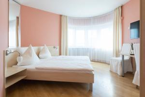 a bedroom with a white bed and a large window at Hotel Martin in Limburg an der Lahn