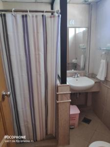a bathroom with a shower curtain and a sink at Flora Place Hotel in Kota Bharu