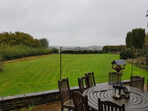 a circular table with chairs and a field in the background at House On The Hill in Little Massingham