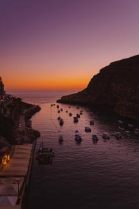 a group of boats in the water at sunset at Hotel San Andrea in Xlendi