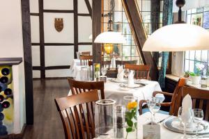 a dining room with a white table with chairs and lights at Hotel-Restaurant Zum Schwanen in Wermelskirchen